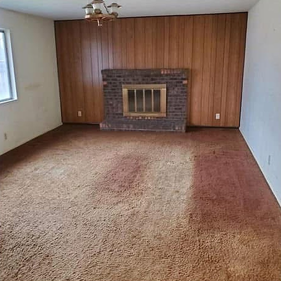 Living room before remodel with wood paneling and old carpet