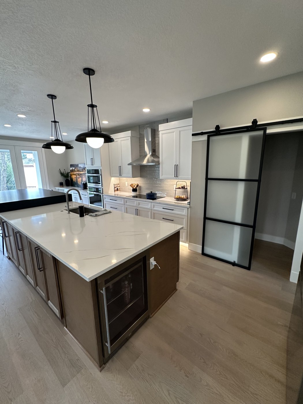 Finished kitchen remodel with quartz waterfall island and barn door